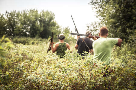 Hunting scene with hunters breakthrough thickets during hunting season in hot summer dayの写真素材