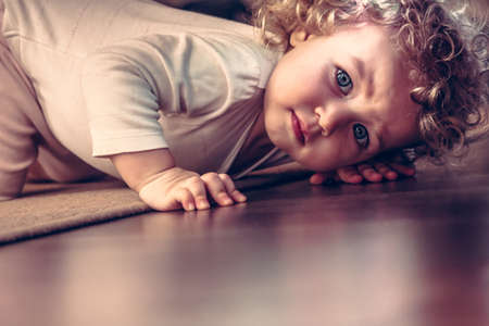 Scared child hiding under the bed in kid room and looking scaredの写真素材