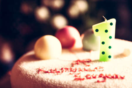 Happy birthday cake for children party decorated with one candle and sweet balloons in honour of first birthday anniversary as happy birthday backgroundの写真素材