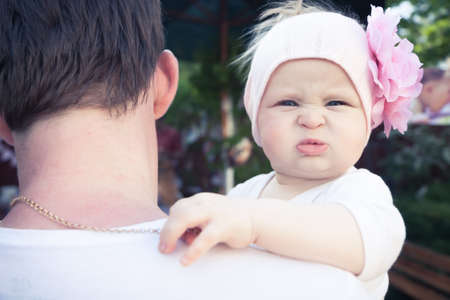 Father embracing his cute little baby. Father is looking away, baby with funny face is looking on camera and embracing his father neck.の写真素材