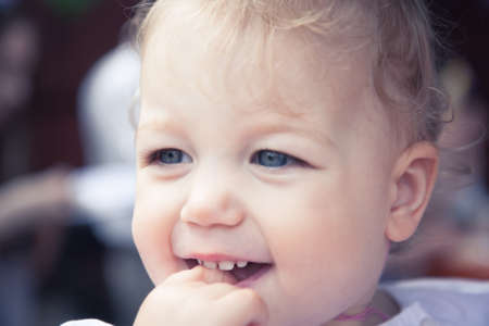 Cute smiling fascinated baby girl portrait with finger in mouthの写真素材