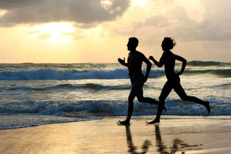 Woman and men running during sunset の写真素材