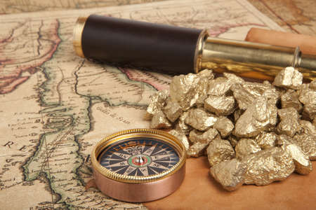 Gold nuggets and vintage brass telescope on antique map