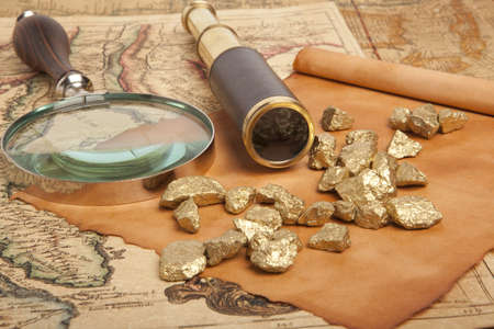 Gold nuggets and vintage brass telescope on antique mapの写真素材