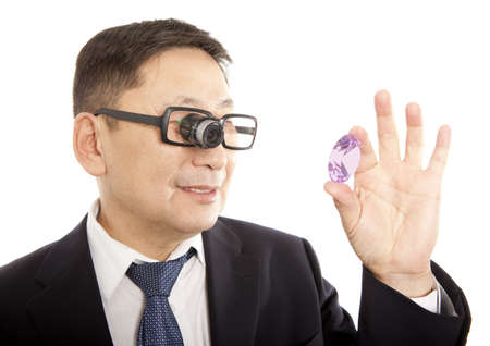 Male jeweler looking through a magnifier to check for flaws in a sapphireの写真素材