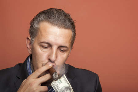 Man lighting his cigar with 100 dollars banknoteの写真素材