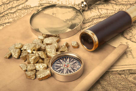 Gold nuggets and vintage brass telescope on antique mapの写真素材