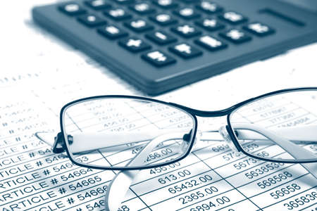 Glasses and calculator on paper table with finance report Glasses and calculator on paper table with finance report