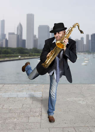 Saxophonist. Middle aged man playing on saxophone against the background of skyscraper