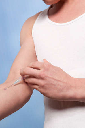 Drug addict man with syringe in actionの写真素材