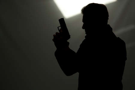 one man killer policeman aiming gun silhouette studio grey backgroundの写真素材
