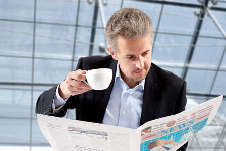 Businessman reading a newspaper while drinking coffeeの写真素材