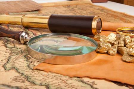 Gold nuggets and vintage brass telescope on antique map 