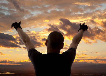Man with his hands up on the dawn on the riverの写真素材