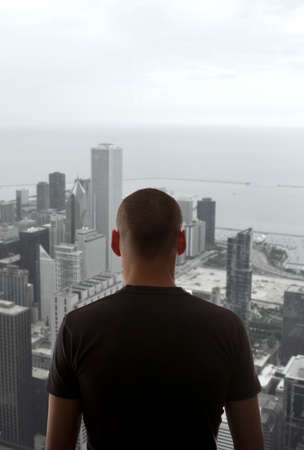 Men standing on the rooftop of a skyscraper over a cityscapeの写真素材