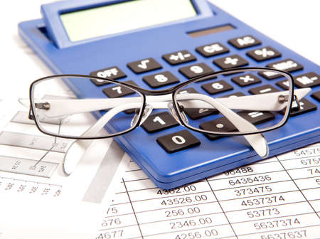 Glasses and calculator on paper table with finance reportの写真素材