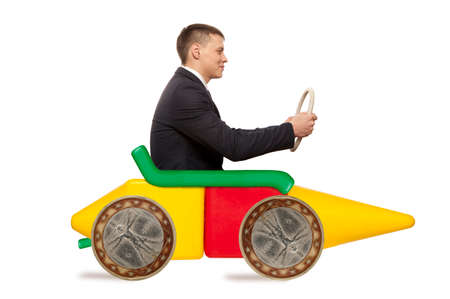 Young businessman driving fast on a toy carの写真素材
