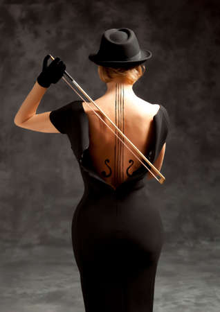 Woman in a black dress and black hat plays the violinの写真素材