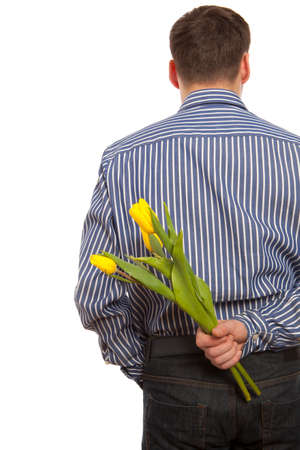Man hiding bouquet of flowers tulip behind his back isolated on white backgroundの写真素材