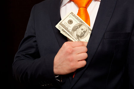 Businessman putting money in suit jacket pocket, concept for corruption, bribing