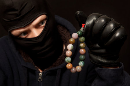 Thief. Man in black mask with a jade necklace. Focus on necklaceの写真素材
