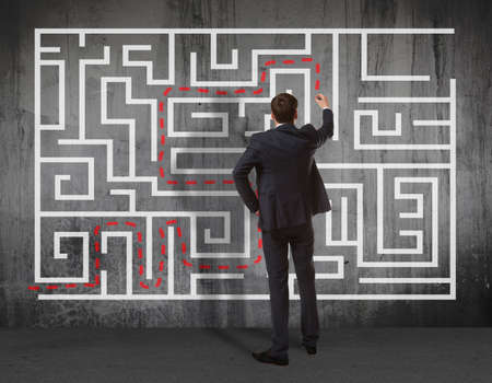 Business concept. Back view of businessman drawing labyrinth on wallの写真素材