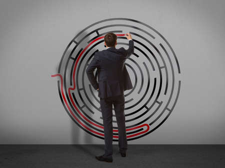Business concept. Back view of businessman drawing labyrinth on wallの写真素材