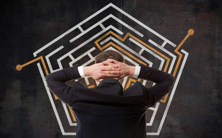 Business concept. Back view of businessman looking at a maze on wallの写真素材