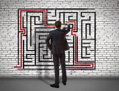 Business concept. Back view of businessman drawing labyrinth on wallの写真素材