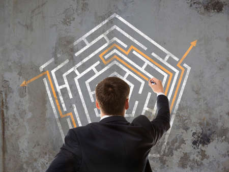 Business concept. Back view of businessman looking at a maze on wallの写真素材