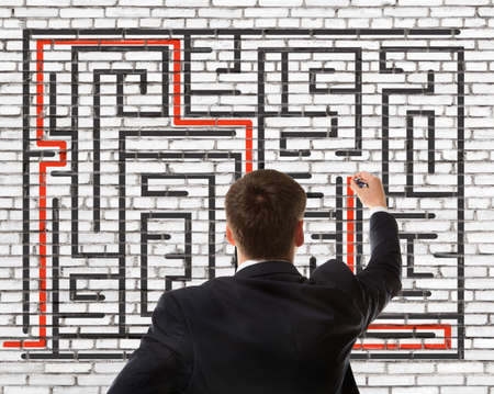 Business concept. Back view of businessman looking at a maze on wallの写真素材