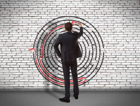 Business concept. Back view of businessman drawing labyrinth on wallの写真素材