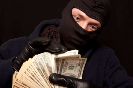 Thief and cash. Showing a thief counting the moneyの写真素材