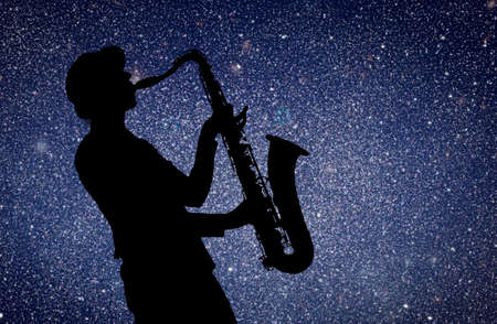 Saxophonist. Woman playing on saxophone against the background of starry skyの写真素材