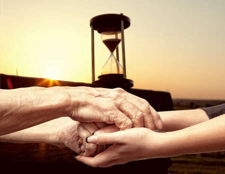 Hands of an elderly senior holding the hand of a younger womanの写真素材