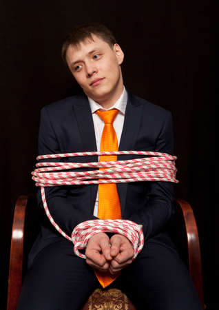 Businessman with hands tied in ropesの写真素材