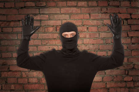Thief with balaclava caught in front of the wallの写真素材