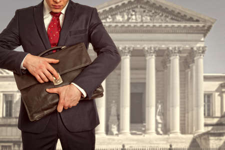 The lawyer with a briefcase is on against the courthouseの写真素材