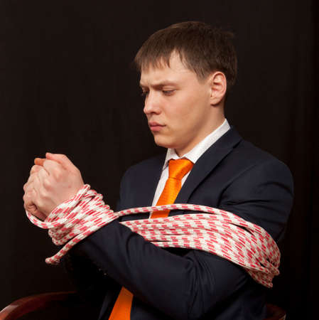 Businessman with hands tied in ropesの写真素材