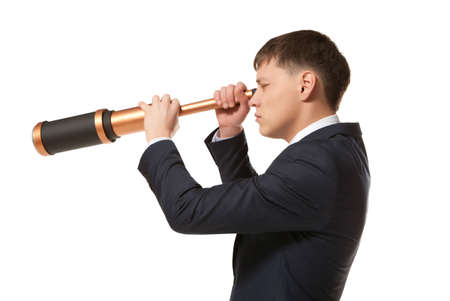 Business concept. Businessman looks through a telescope isolated on whiteの写真素材