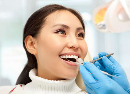 Young woman keeping her mouth open while dentist examining it. Dental photo seriesの写真素材