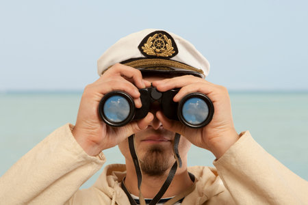 Captain looks through a binoculars. Marine concept