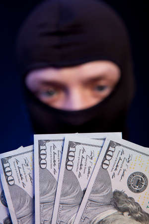 Thief. Man in black mask holding the moneyの写真素材