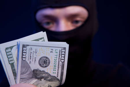 Thief. Man in black mask holding the moneyの写真素材