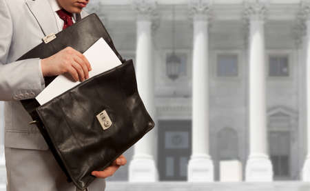 The lawyer with a briefcase is on against the courthouseの写真素材