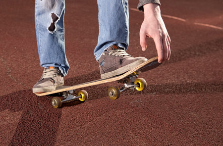 Teenager doing exercises on a skateboard on the road