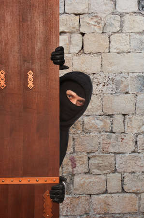 Ninja. Robber hiding behind a wooden doors with space for textの写真素材