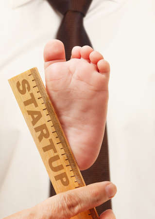 Business concepts start-up. Newborn baby feet in mother hands and rulerの写真素材