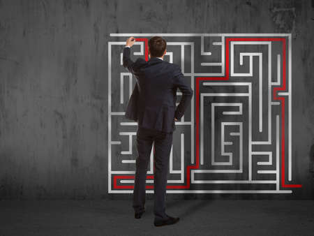 Business concept. Back view of businessman drawing labyrinth on wallの写真素材