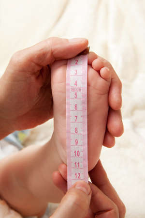 Business concepts startup. Newborn baby feet in mother hands and rulerの写真素材